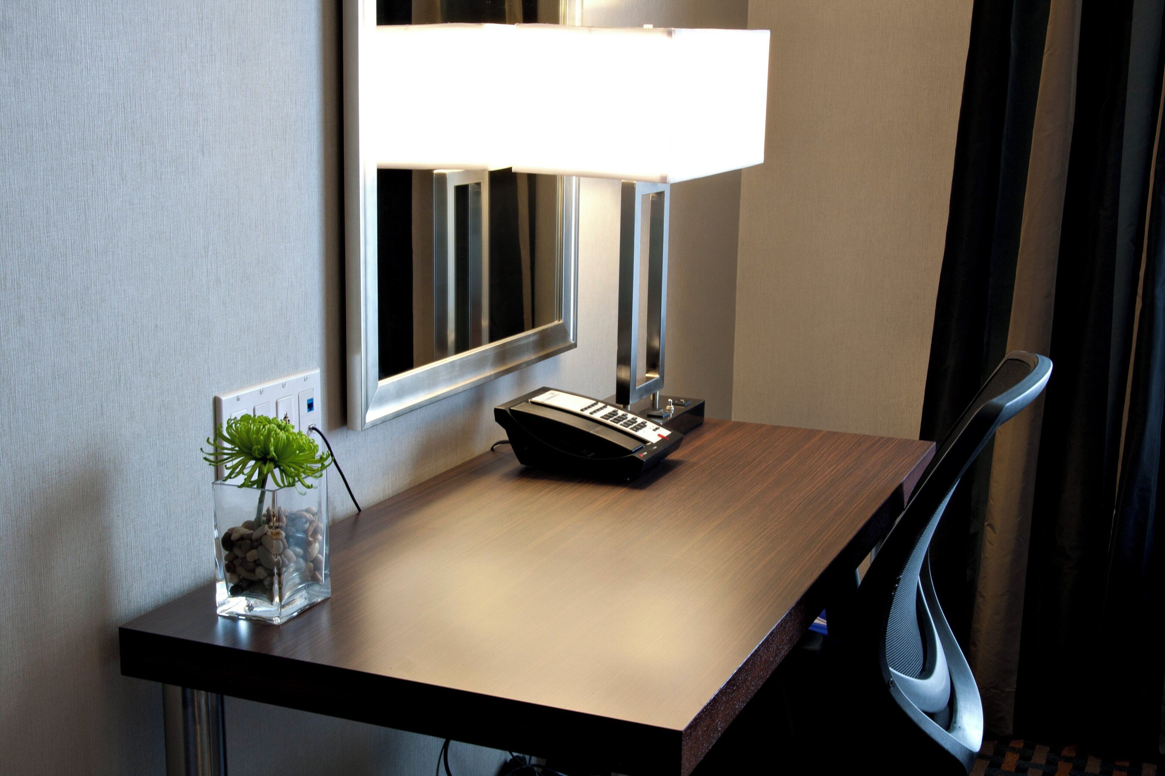 Un bureau d’hôtel avec une lampe, un clavier et une petite plante.
