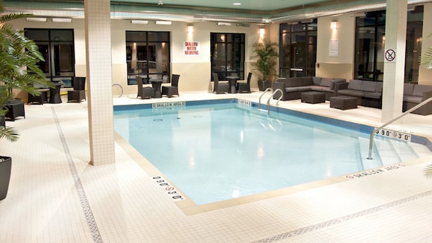 An indoor swimming pool with a shallow area marked, surrounded by seating and a sign indicating shallow water. - Holiday Inn Express Pembroke by IHG (Pembroke)