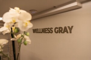 Una pared con el texto "WELLNESS GRAY" y una orquídea en maceta.