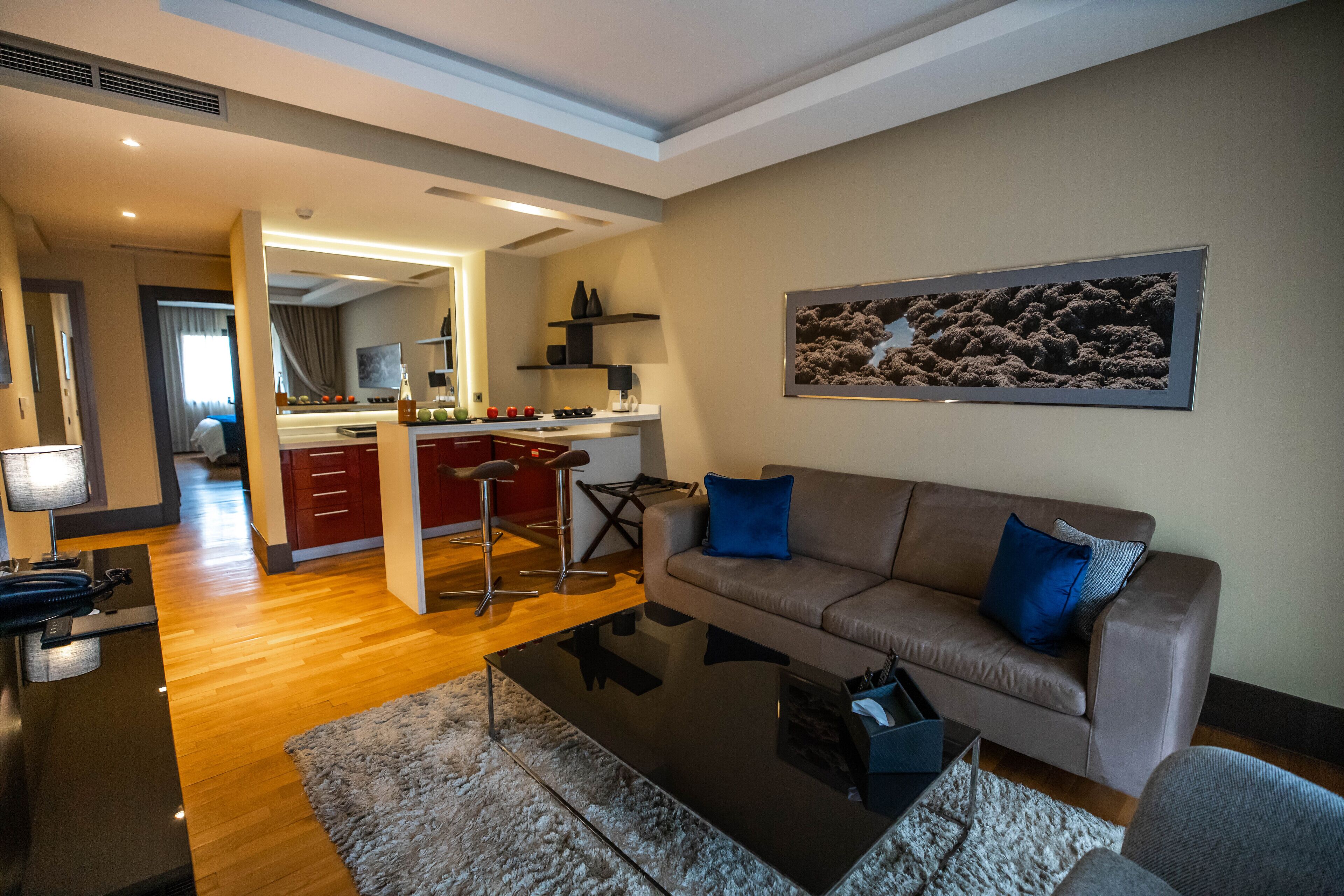 A modern living room with a sofa, coffee table, and a kitchen area in the background.