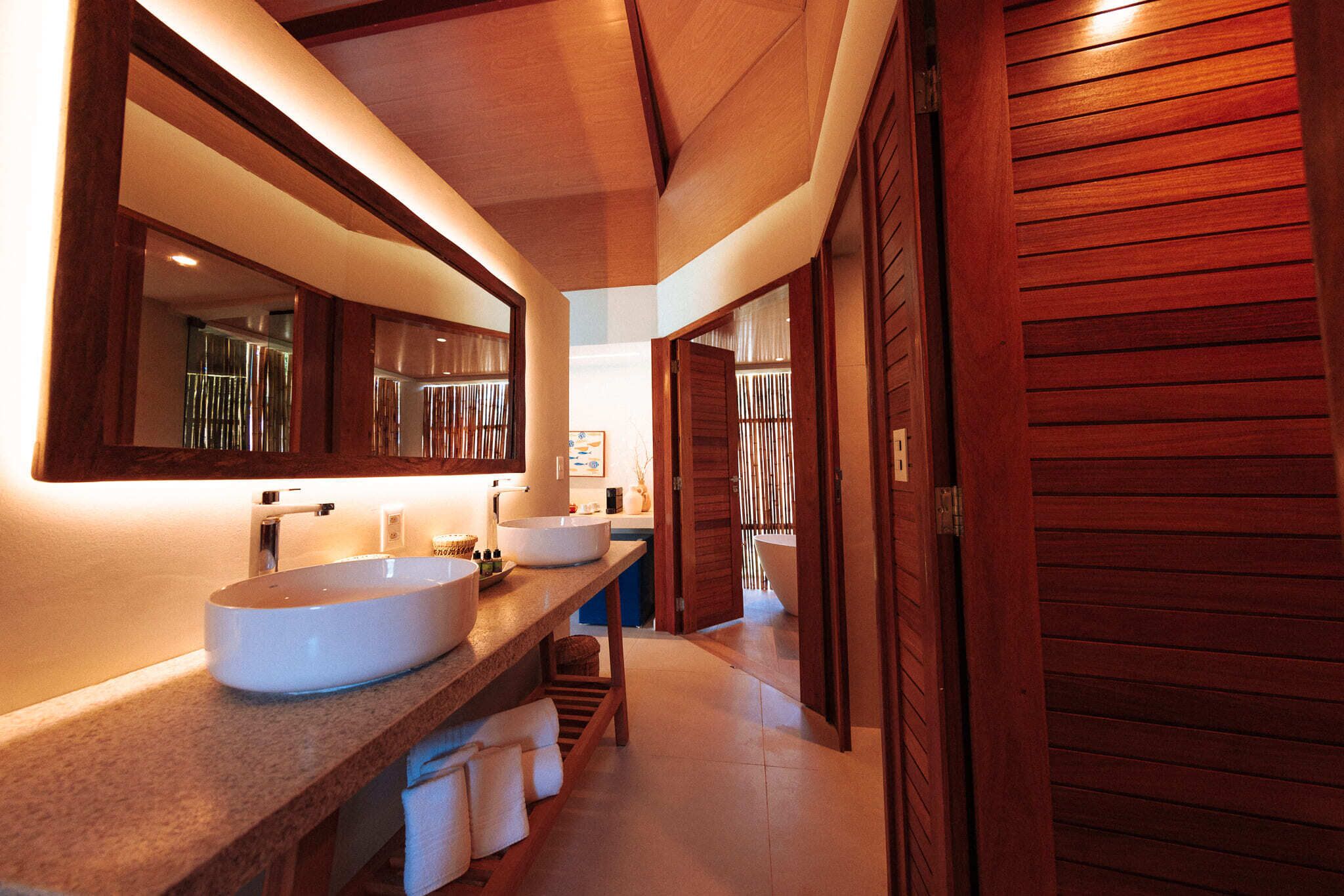 A modern bathroom with two large sinks, a mirror, and wooden doors.