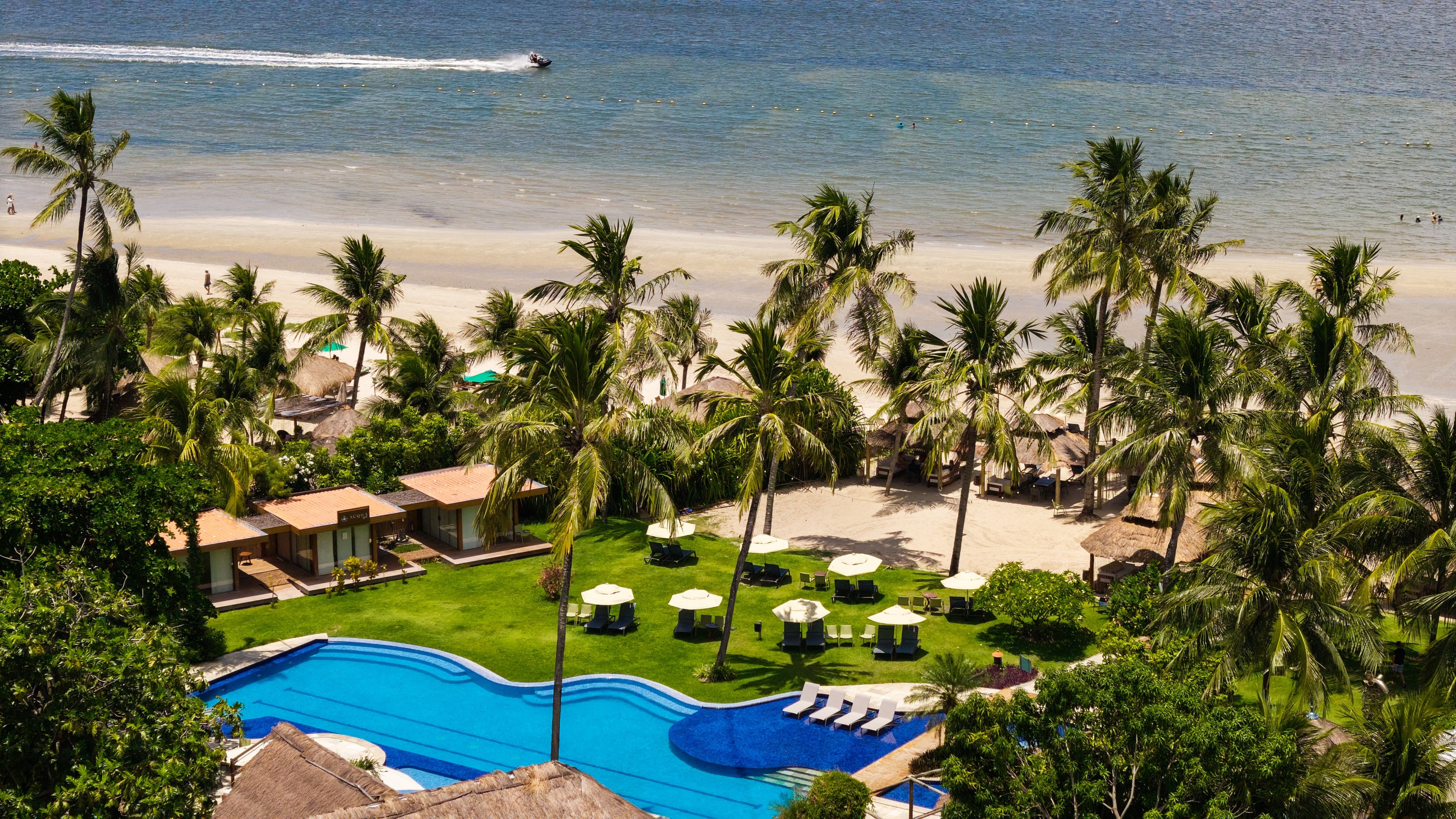 Un resort con piscina, playa y palmeras.