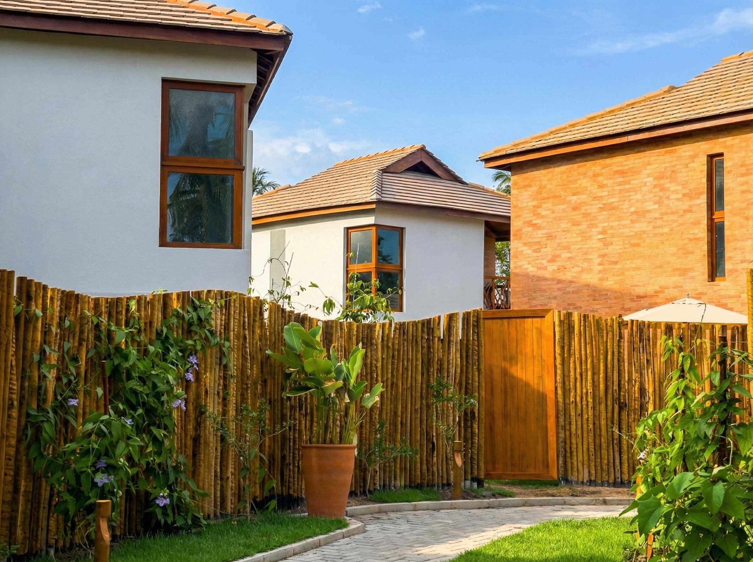 Un immobile residenziale con recinzione in legno, muro in mattoni e tetto in tegole.
