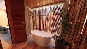 A modern bathroom with a freestanding bathtub, bamboo wall panels, and a potted plant. - Pousada Praia dos Carneiros (Tamandaré)