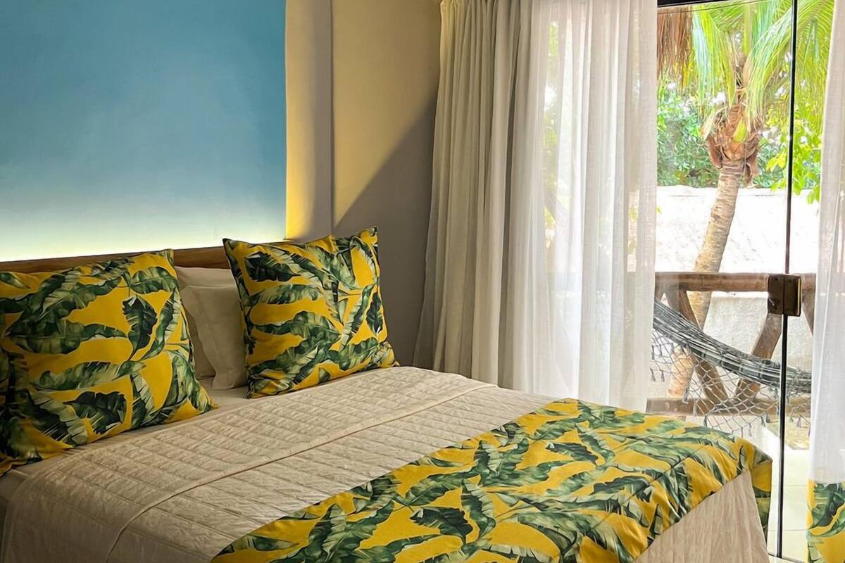 Un dormitorio con cama, vistas al exterior y una hamaca afuera.