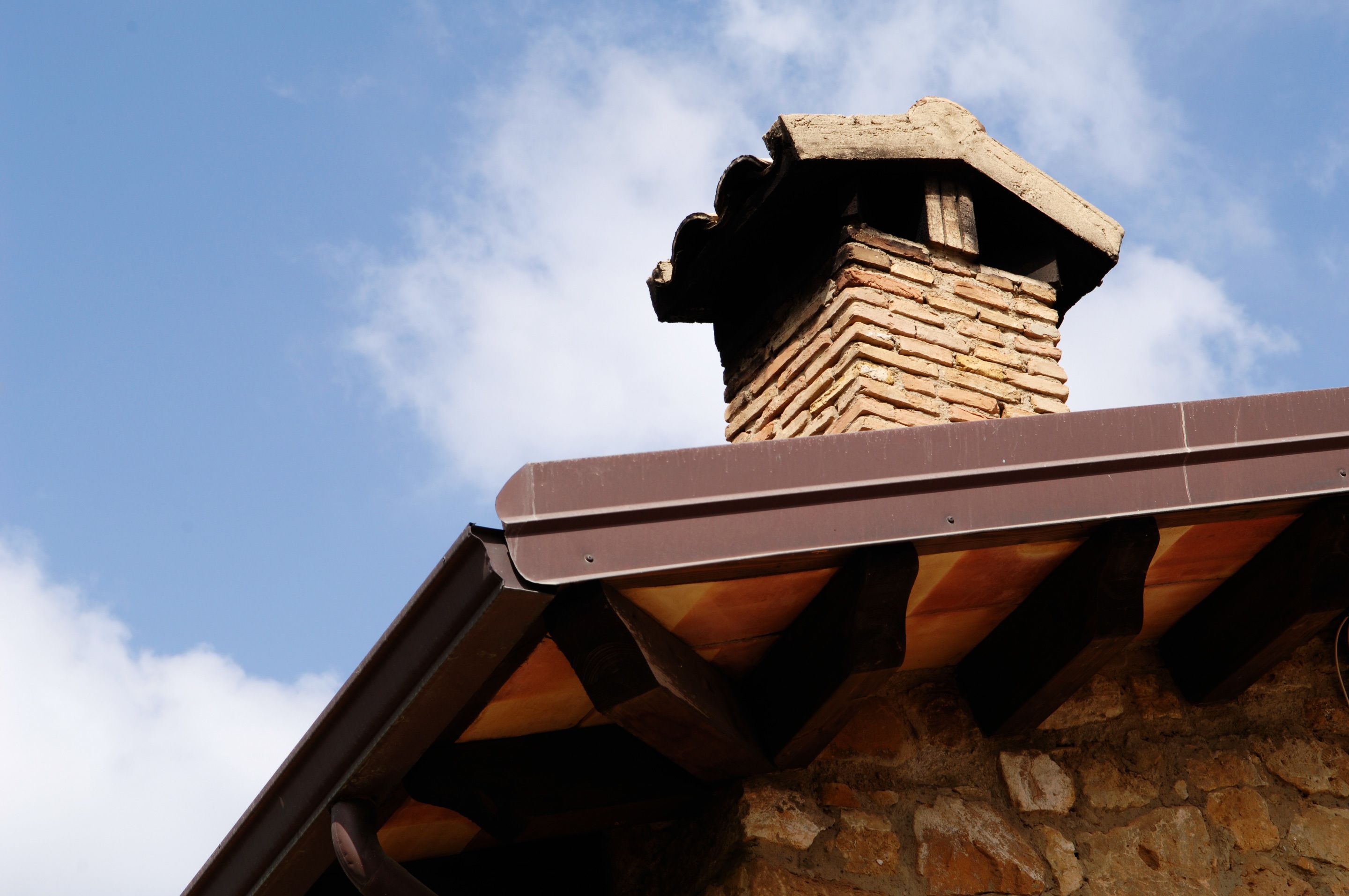 A brick chimney with a metal roof overhang.
