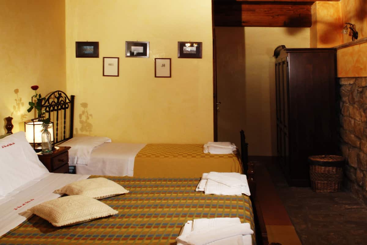 Une chambre d’hôtel avec deux lits, une table de chevet avec une lampe et une cheminée en pierre.