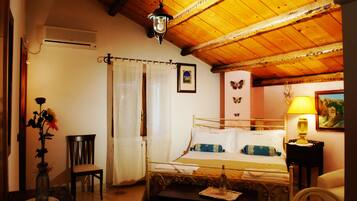 A bedroom with a wooden ceiling, a bed with white bedding, a nightstand with a lamp, a chair, and a vase with flowers.