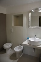 Un baño con inodoro, bidé, lavabo y espejo.