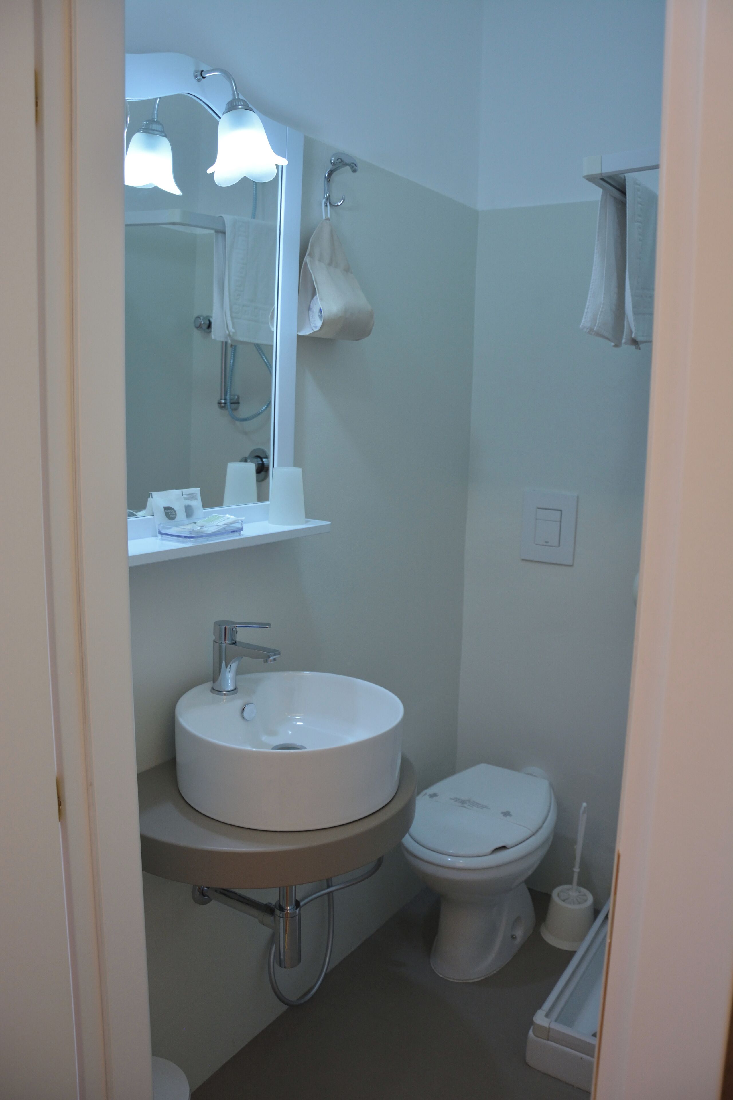 Un baño con lavamanos, espejo e inodoro.