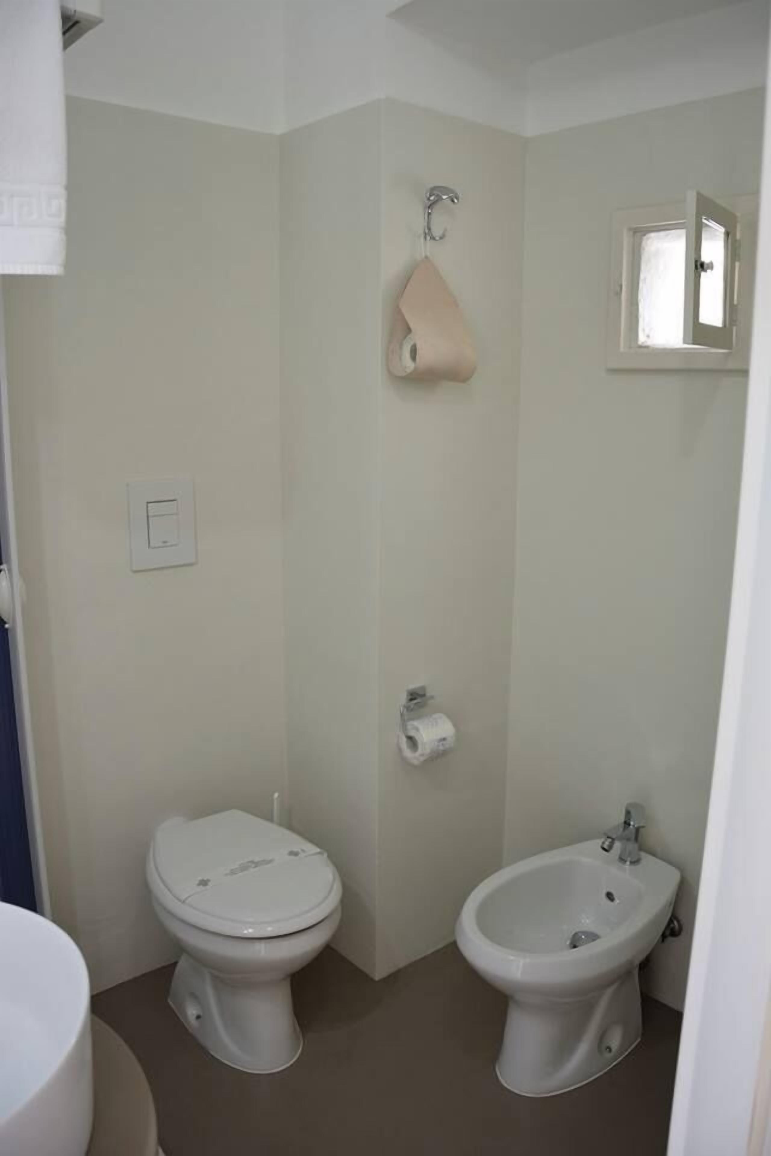 A small bathroom with a toilet, bidet, and a towel rack.