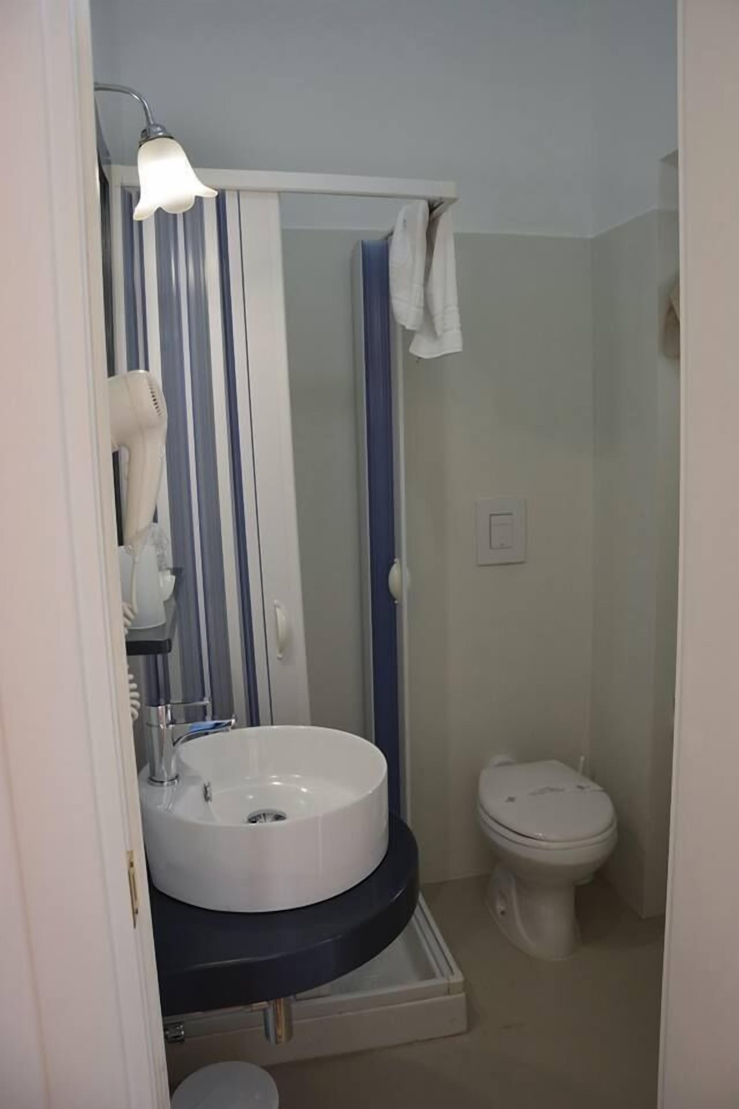 Une salle de bain avec un lavabo blanc, une douche avec un rideau bleu et des toilettes blanches.