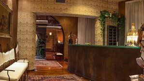 Un vestíbulo de hotel con una recepción, zona de estar y una escalera que sube a un piso superior.