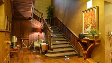 Stunning staircase with polished handrail and wooden paneling, complemented by a beautiful potted plant and elegant artwork.