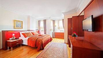 A hotel room with a wooden bed, a TV, a nightstand, and a large window with curtains.