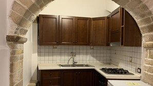Una cocina con armarios de madera, encimera blanca, pileta y estufa.