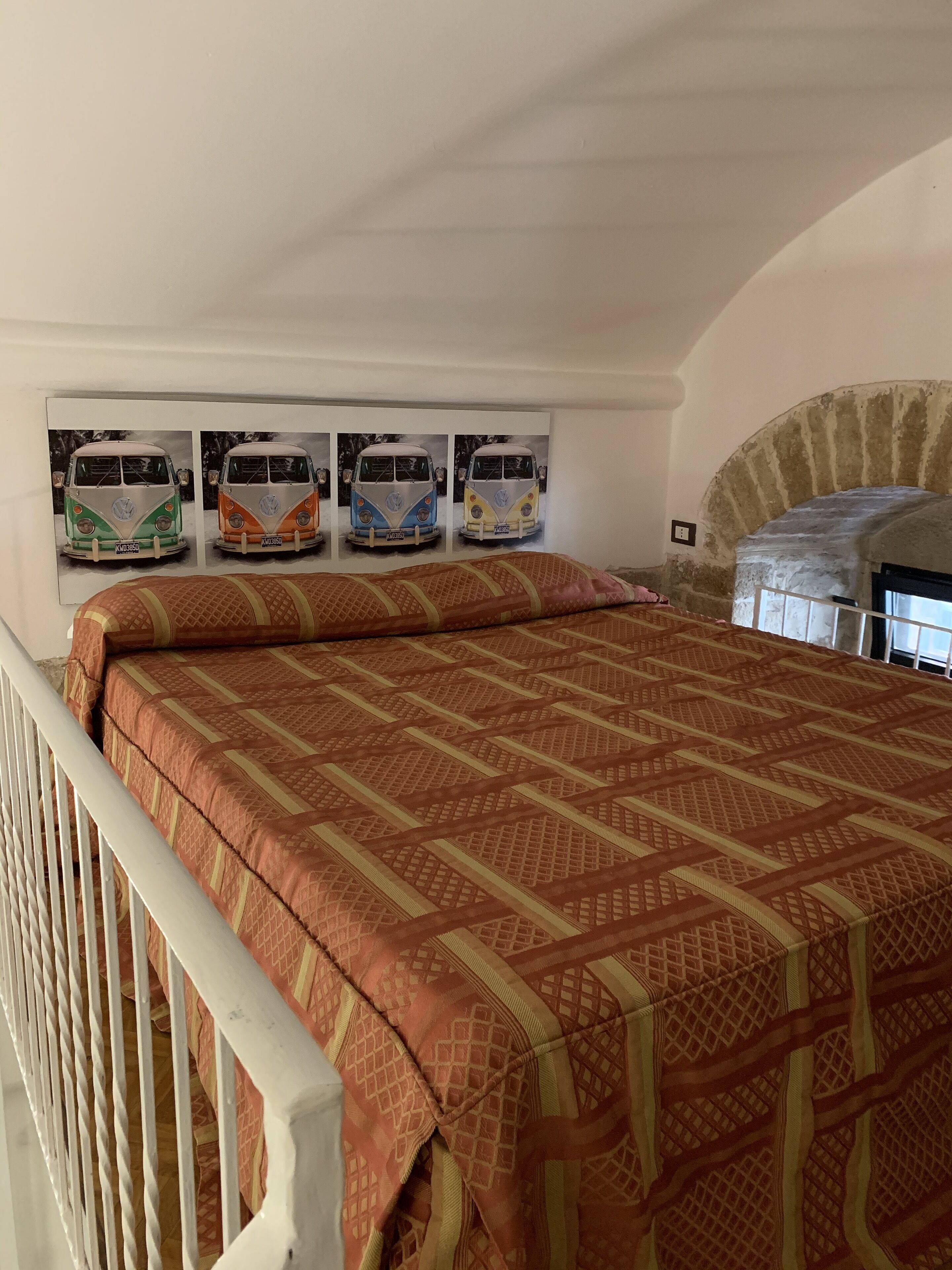 A bedroom with a bed, a crib, and a brick fireplace.