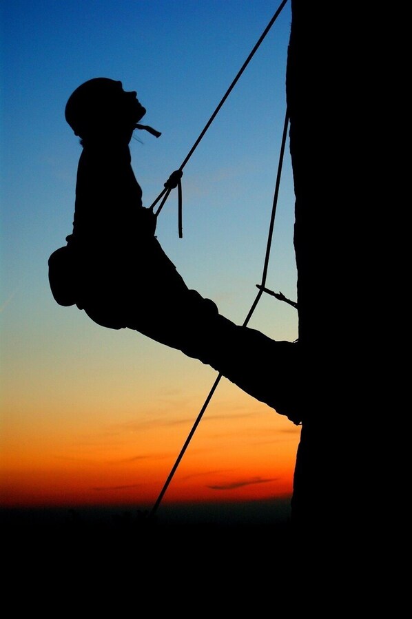 A silhouette of a person climbing a rope against a sunset sky. - Hotel Fajkier Wellness And Spa (Kroczyce)