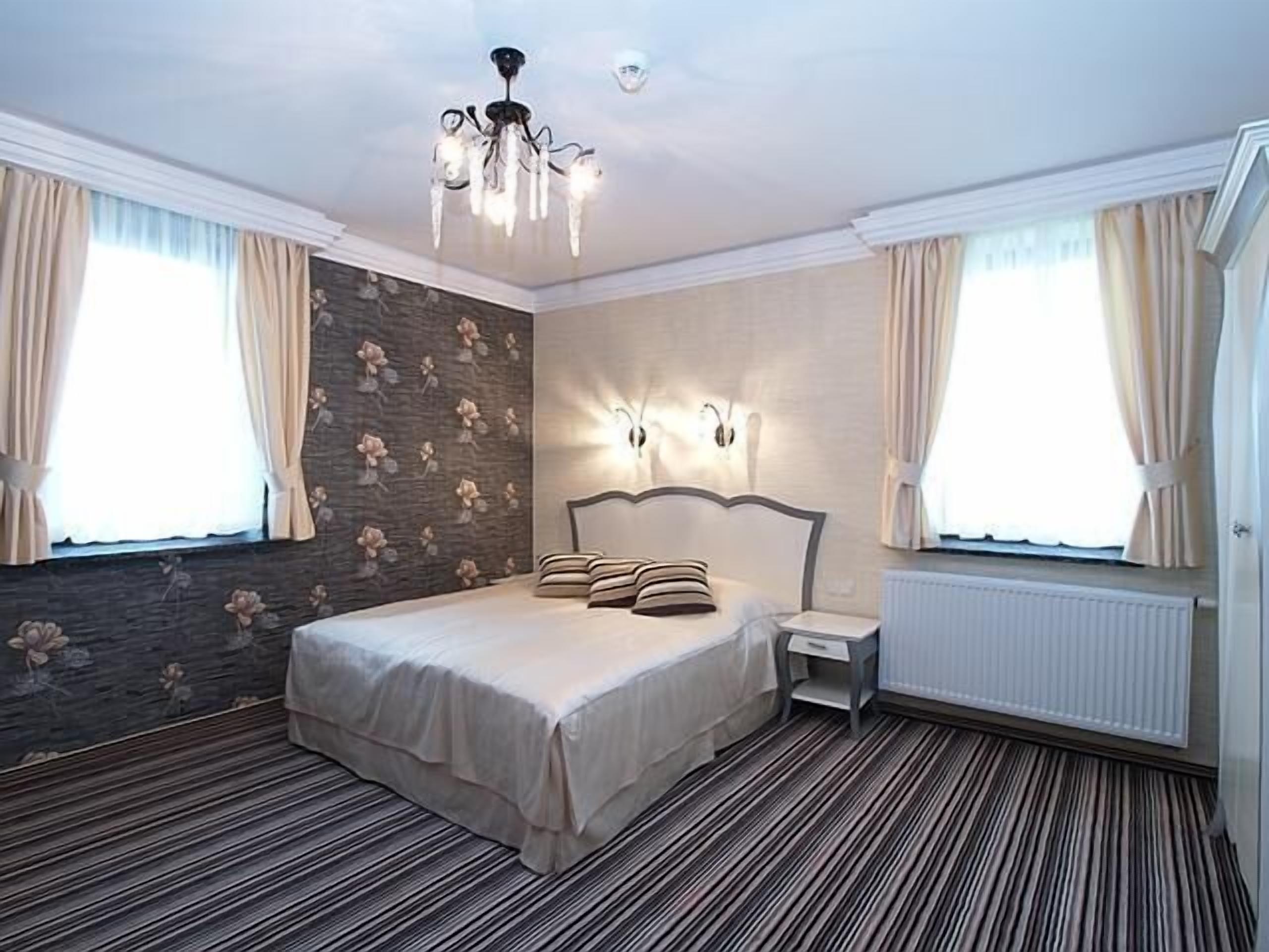 A bedroom with a bed, nightstand, and wall sconces.
