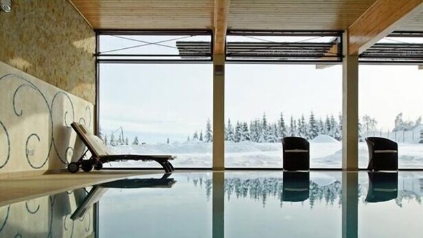 Ein Hallenbad mit freiem Blick auf eine verschneite Landschaft durch große Fenster.
