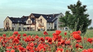 Ein Hotel mit einer symmetrischen Fassade, zahlreichen Balkonen und einem Feld roter Mohnblumen im Vordergrund.