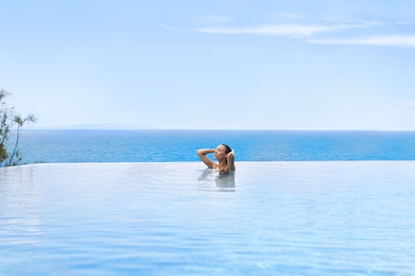 Una piscina al aire libre, sombrillas, sillones reclinables de piscina