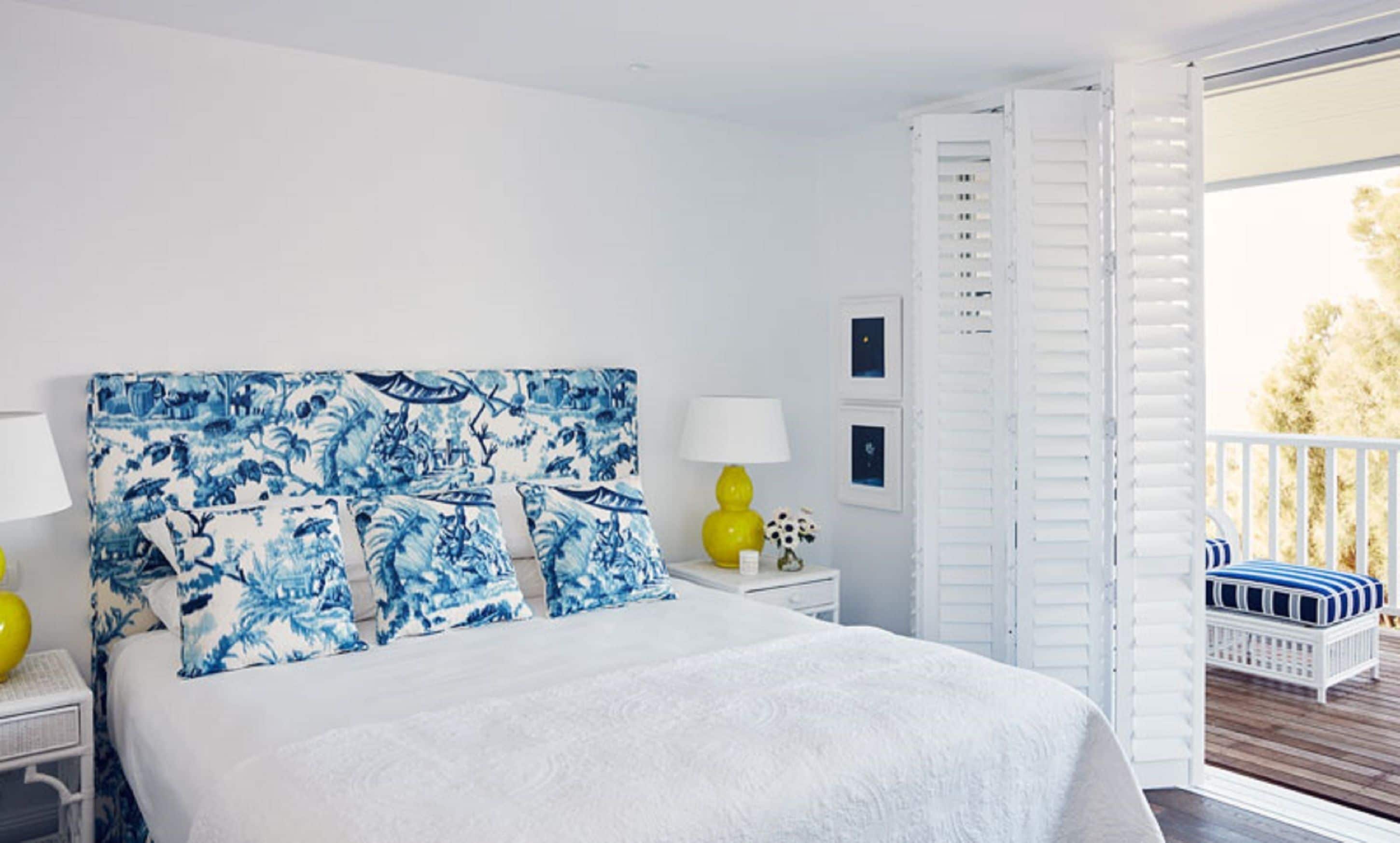 A bedroom with a bed, a nightstand, a lamp, and a view of the outside.
