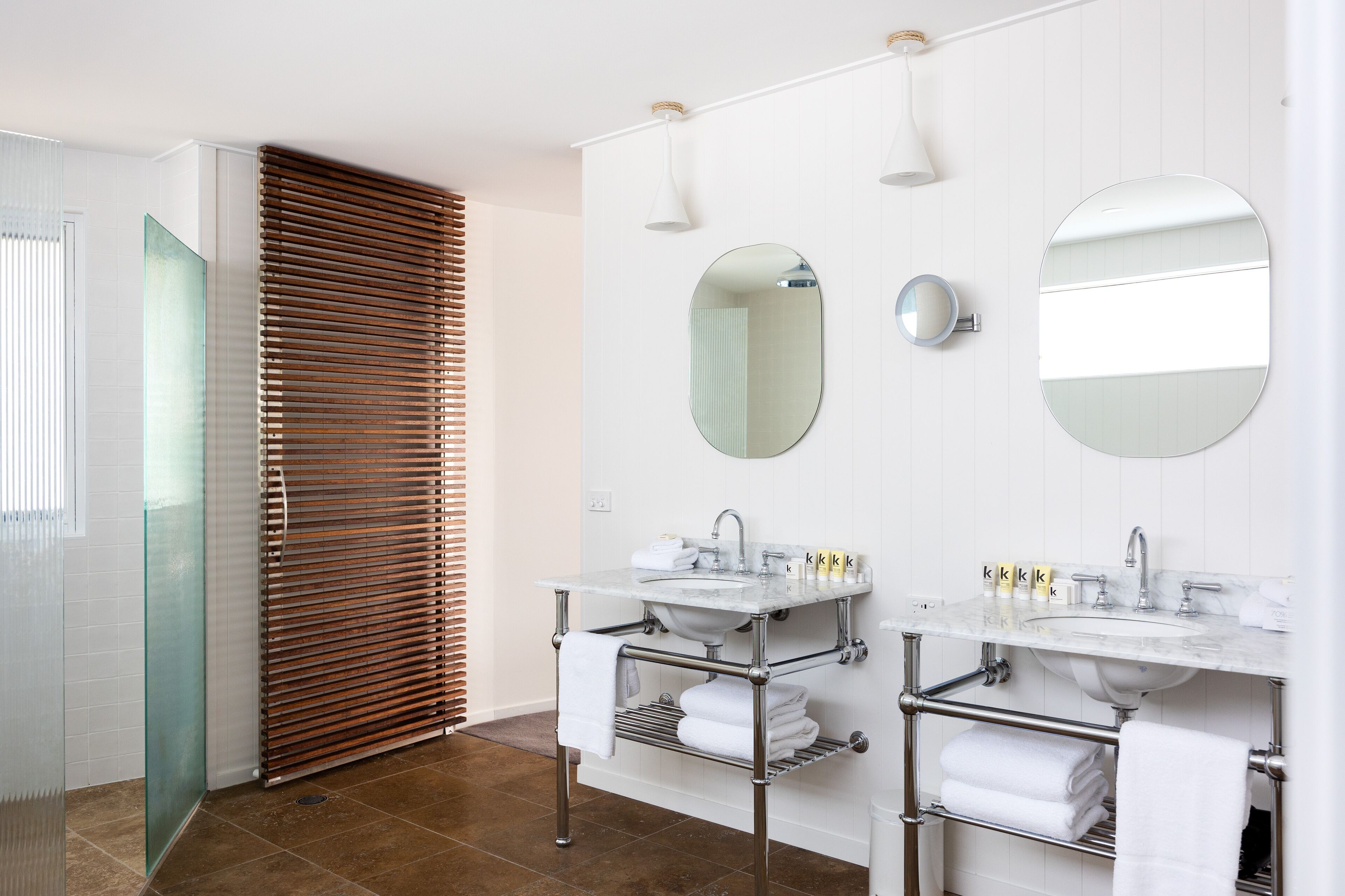 Een moderne badkamer met twee wasbakken, een grote spiegel en een douchecabine met glazen wanden.
