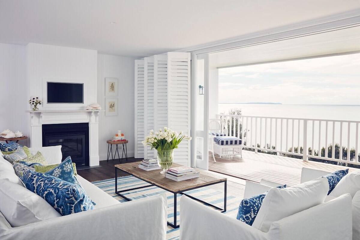 Ein Wohnzimmer mit Kamin, einer Sofagarnitur, einem Couchtisch und einem Balkon mit Blick.