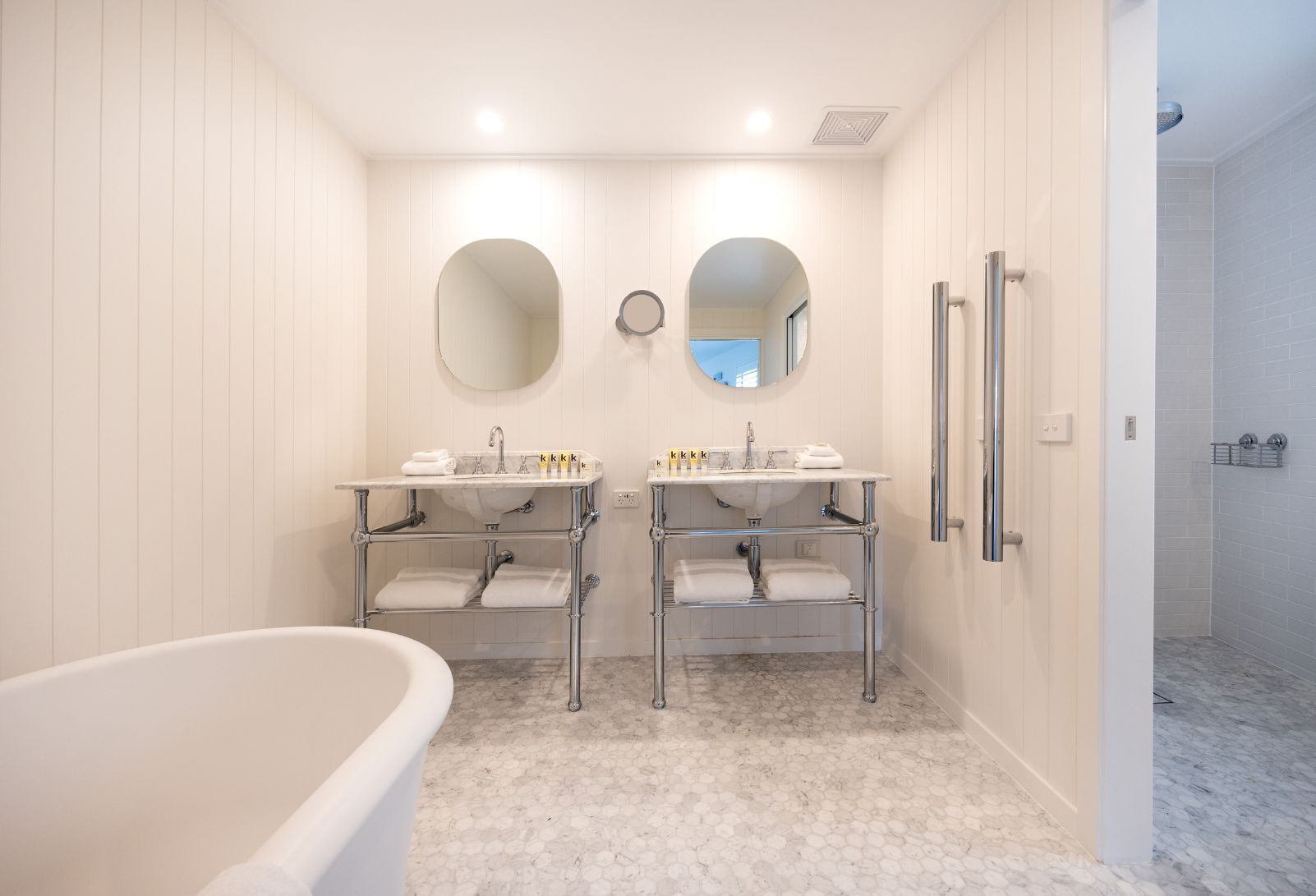 A modern bathroom with two sinks, a bathtub, and a shower.