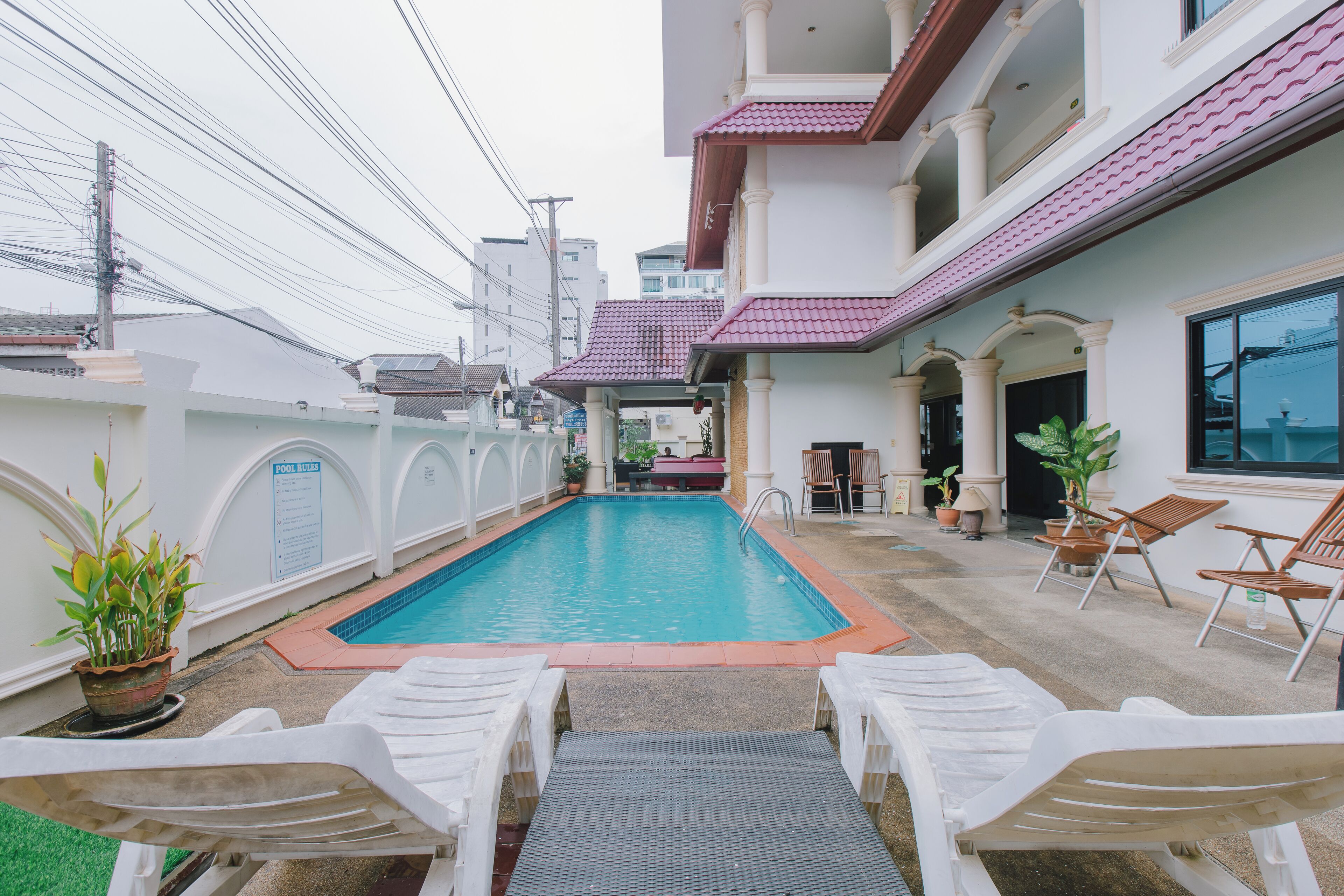 A swimming pool with lounge chairs and a small patio area.
