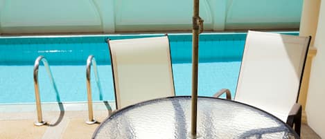 Una piscina al aire libre, sombrillas, sillones reclinables de piscina