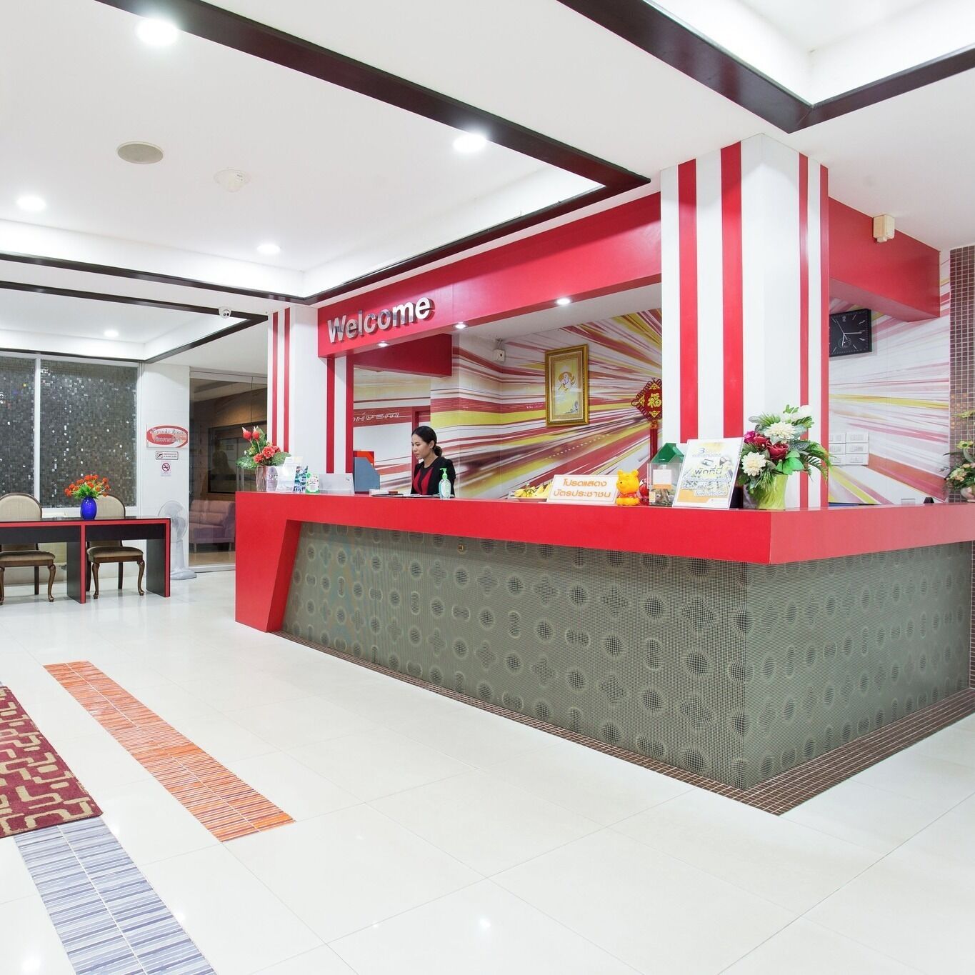A reception desk with a 'Welcome' sign, a clock, and a framed picture on the wall.
