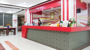 A reception desk with a 'Welcome' sign, a clock, and a framed picture on the wall.