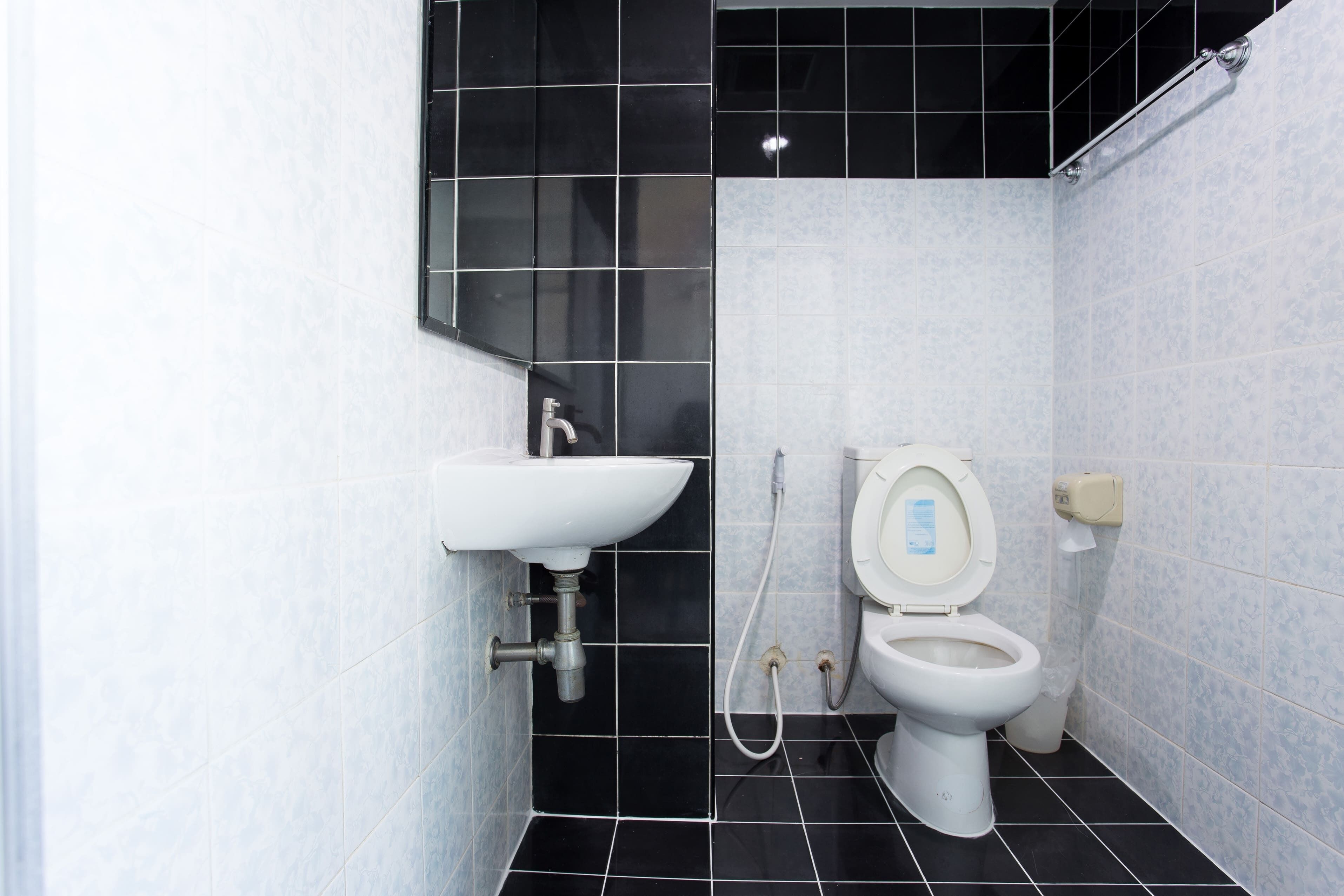 A bathroom with a white sink, a toilet, and black and white tiled walls.