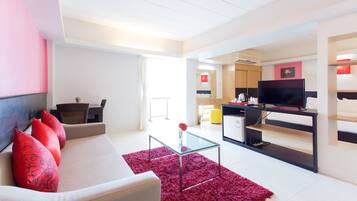 Una sala de estar moderna con un sofá, una mesa de centro y un televisor sobre un mueble.