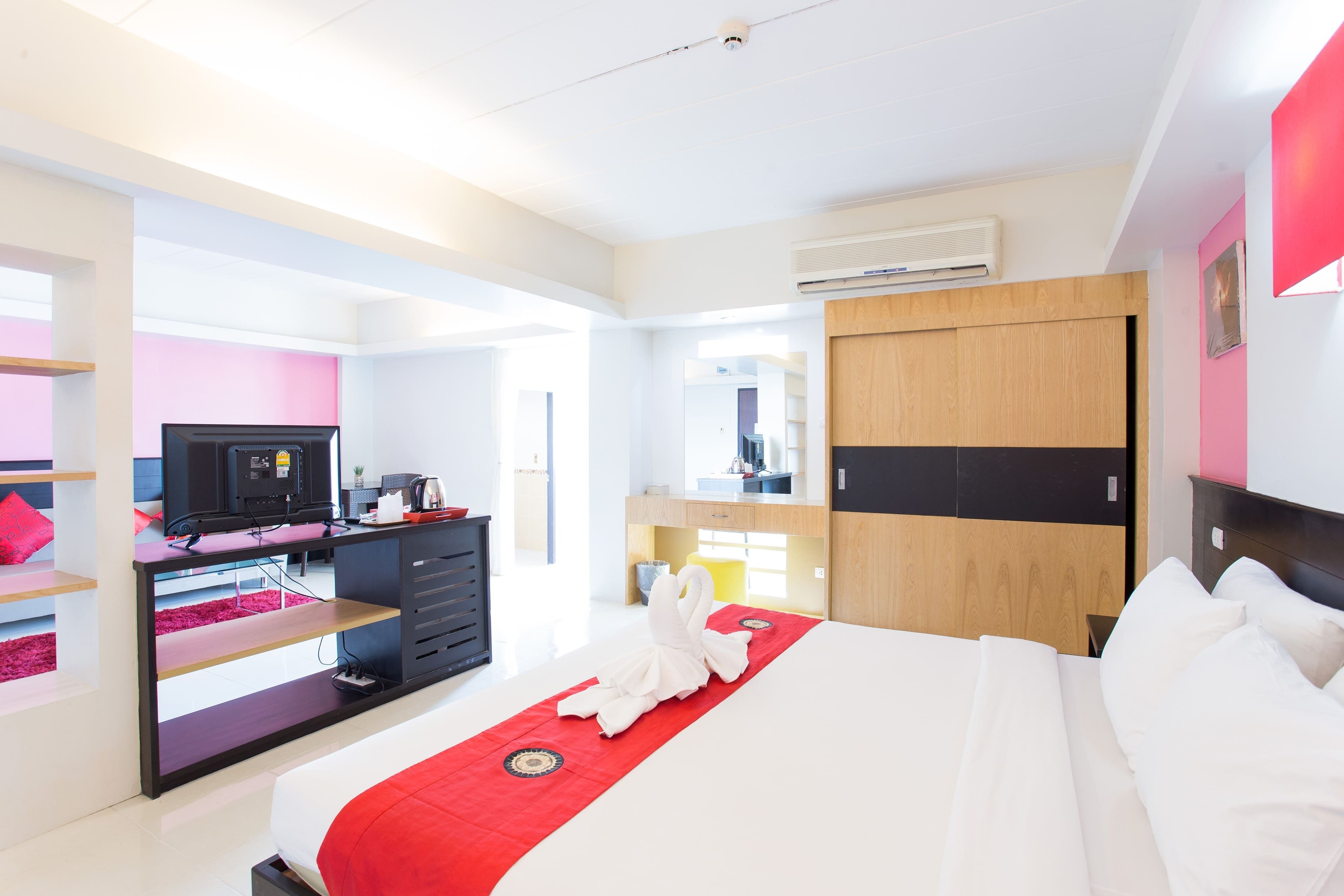 A modern hotel room with a bed, a desk, a TV, and a wardrobe.
