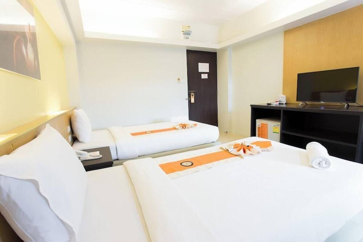 A hotel room with two beds, a TV, a desk, and a door.