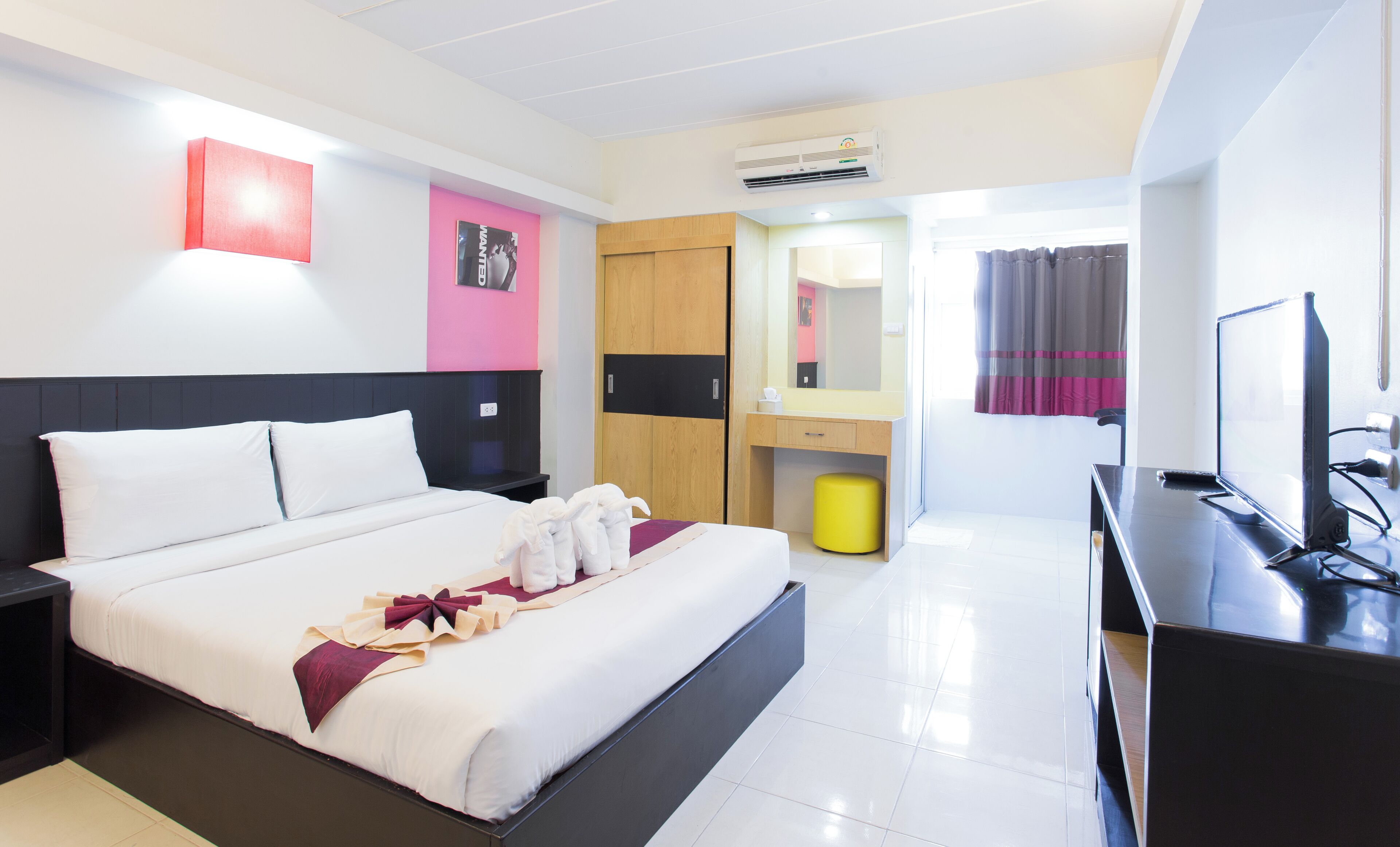 A modern hotel room with a large bed, a desk, a mirror, and a TV.