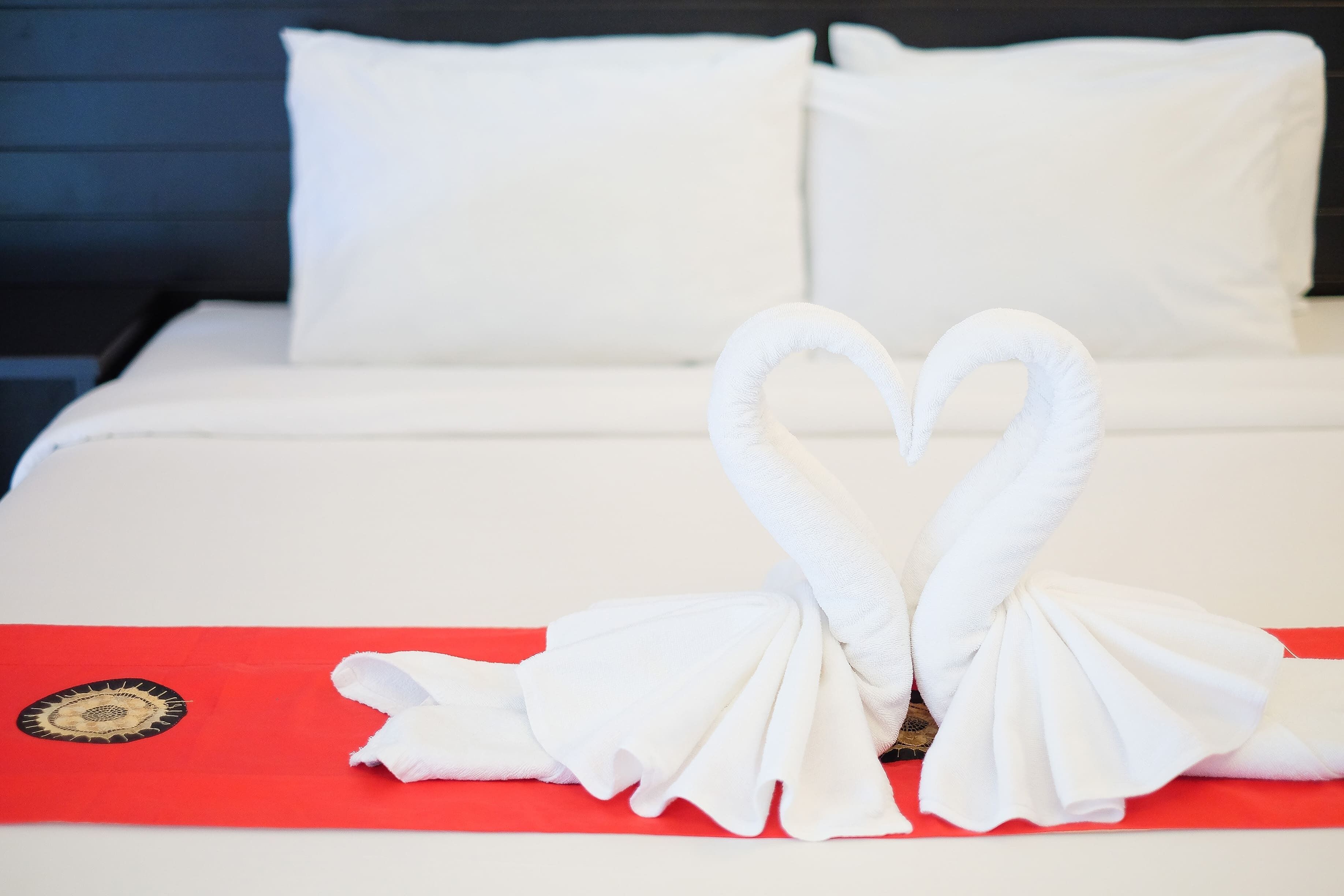 A bed with white linens and a red blanket.
