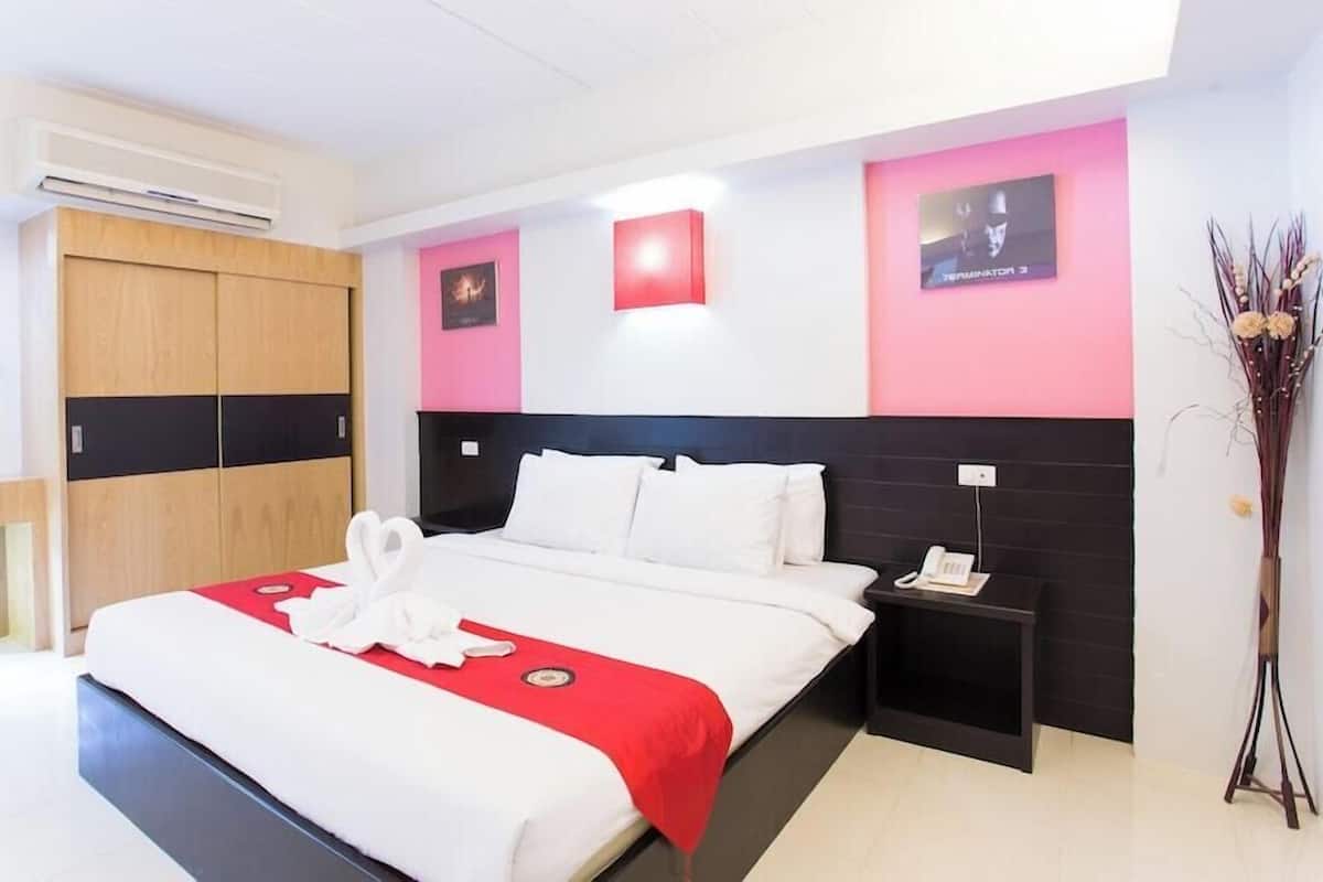 A hotel room with a bed, bedside tables, a wardrobe, and a mirror.