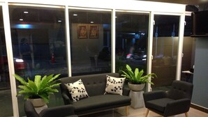 A modern lobby with a sofa, two armchairs, and potted plants. - The Aim Sathorn Hotel (Bangkok)