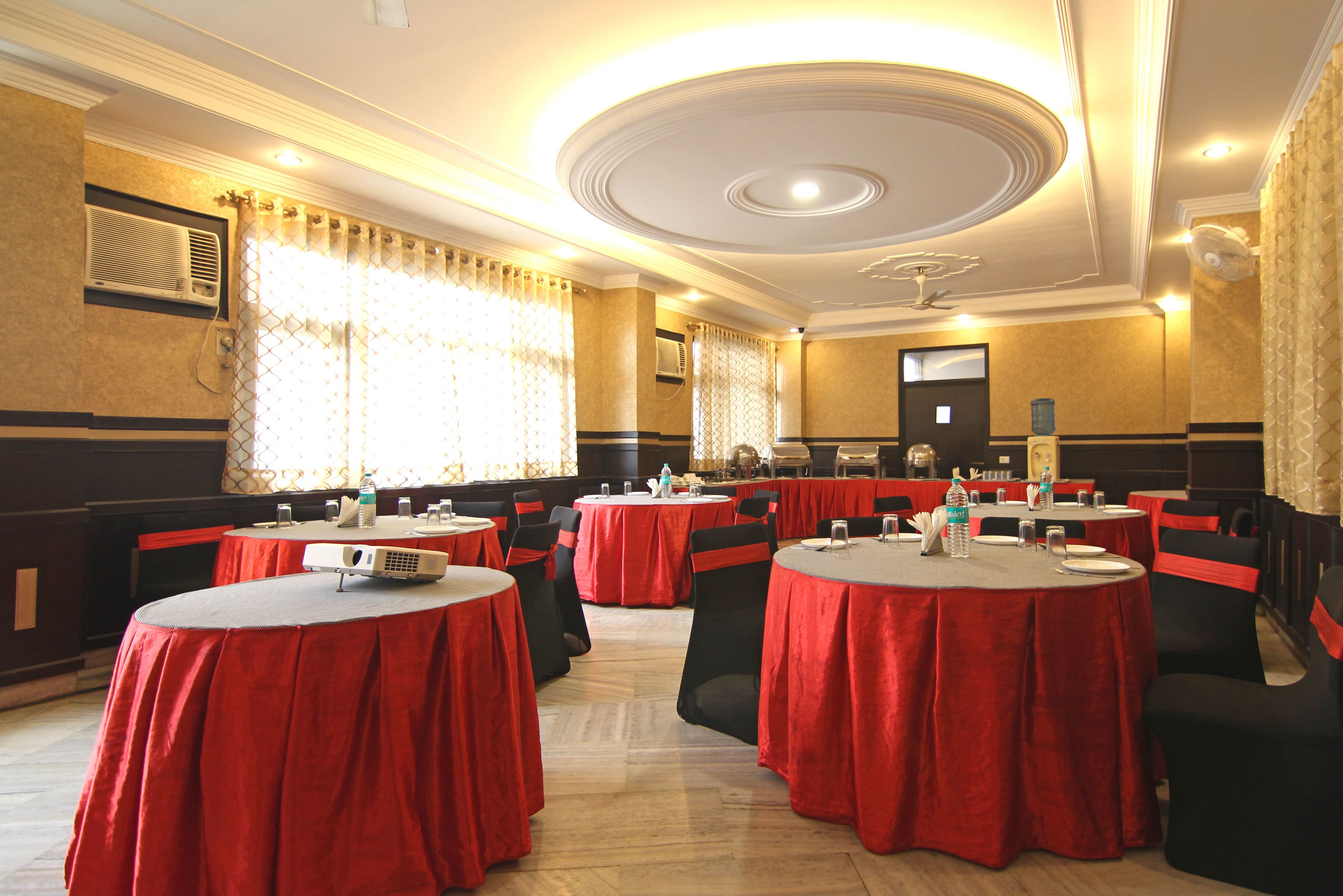 A conference room with round tables, red tablecloths, black chairs, and a ceiling fan.