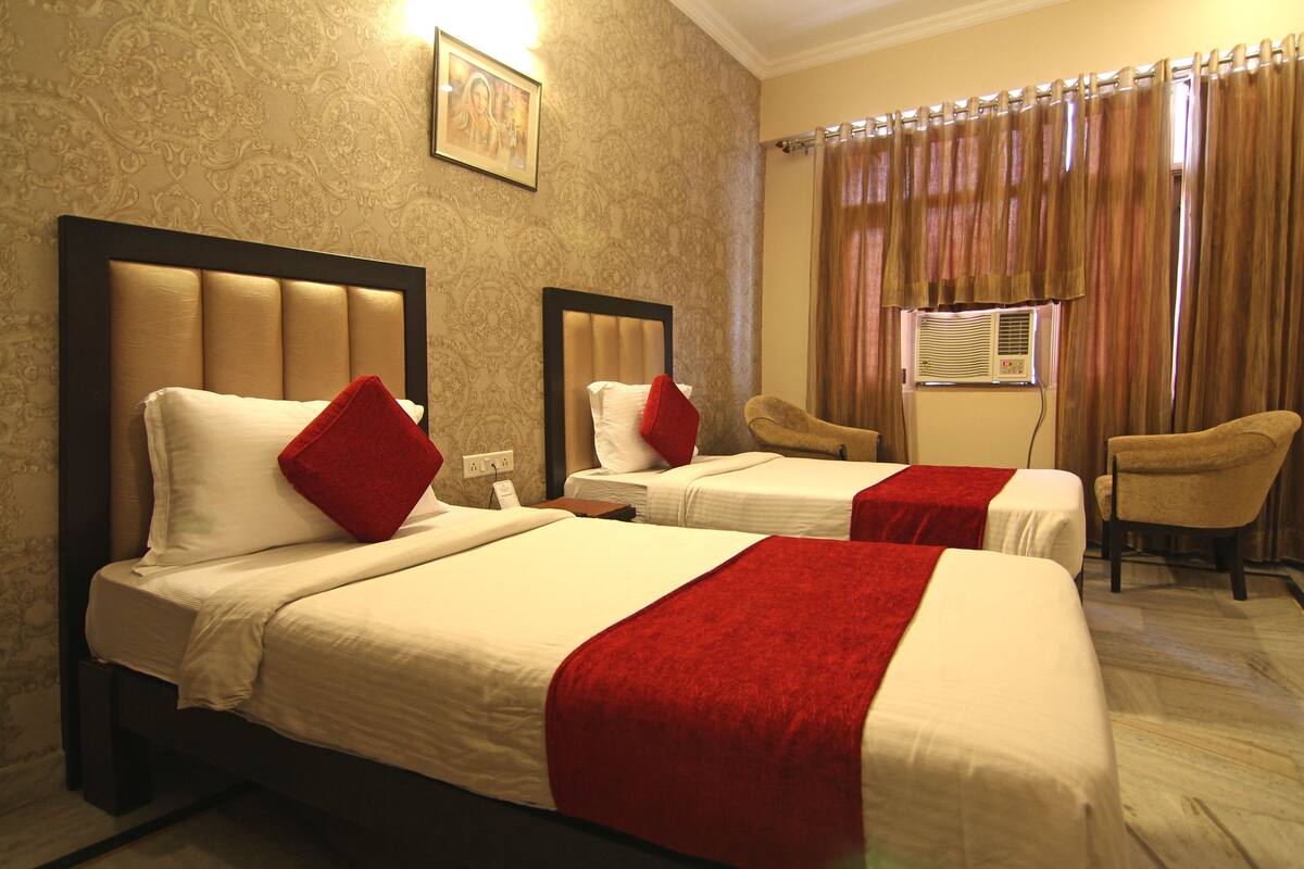 A hotel room with two beds, a chair, and a window with curtains.
