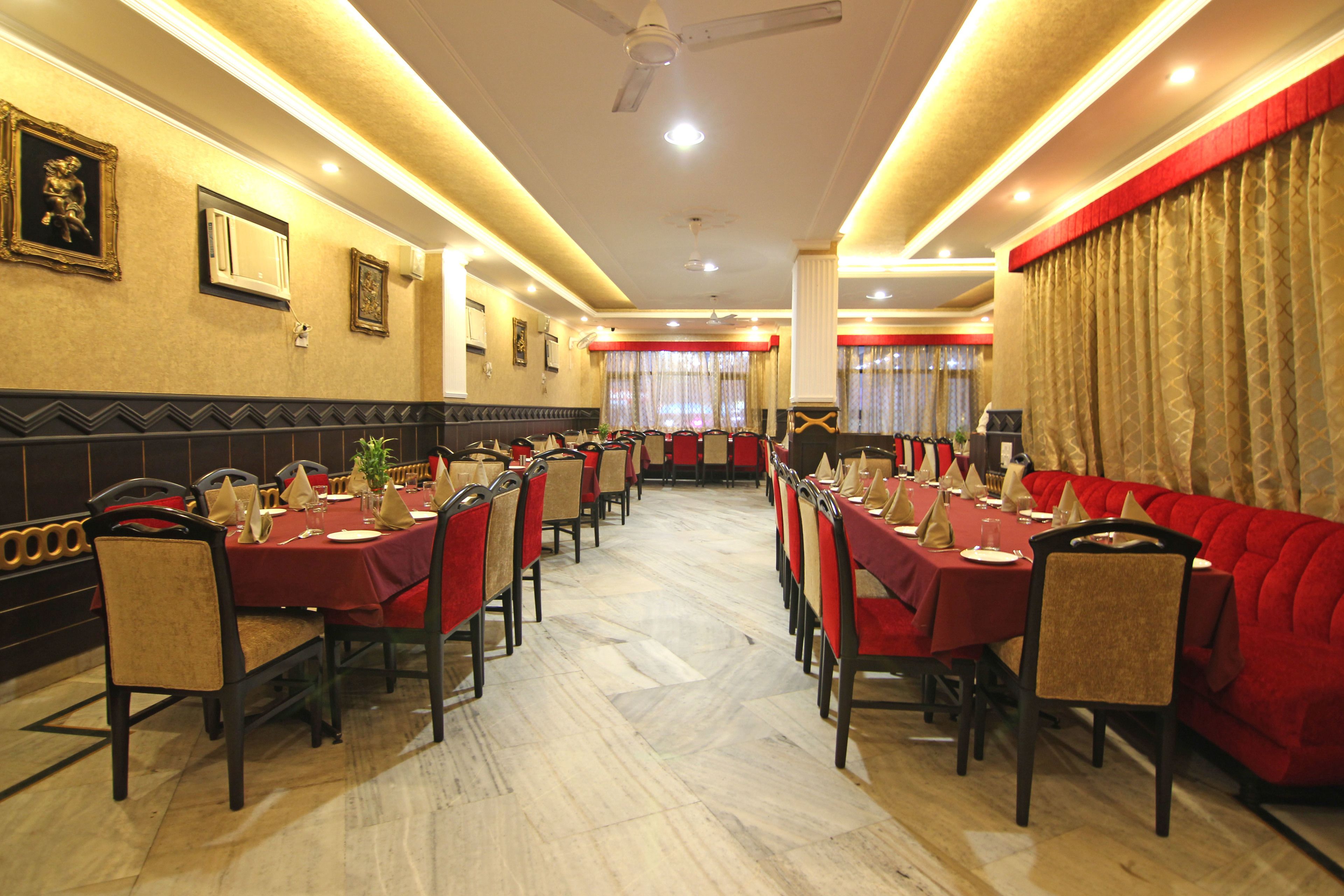 A restaurant with red tablecloths, beige chairs, and a marble floor.