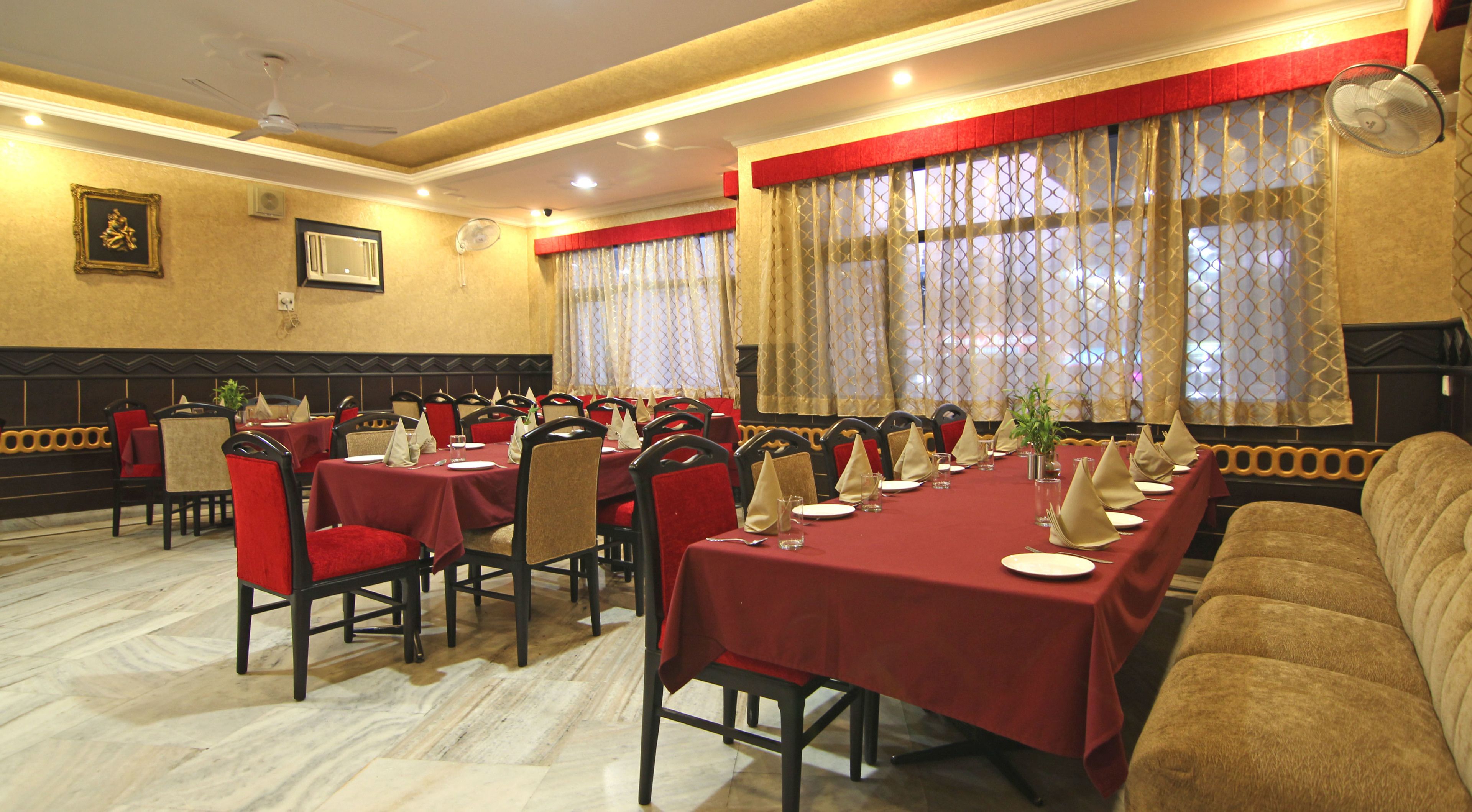 Un comedor con mesas dispuestas para una comida, sillas y un sofá.
