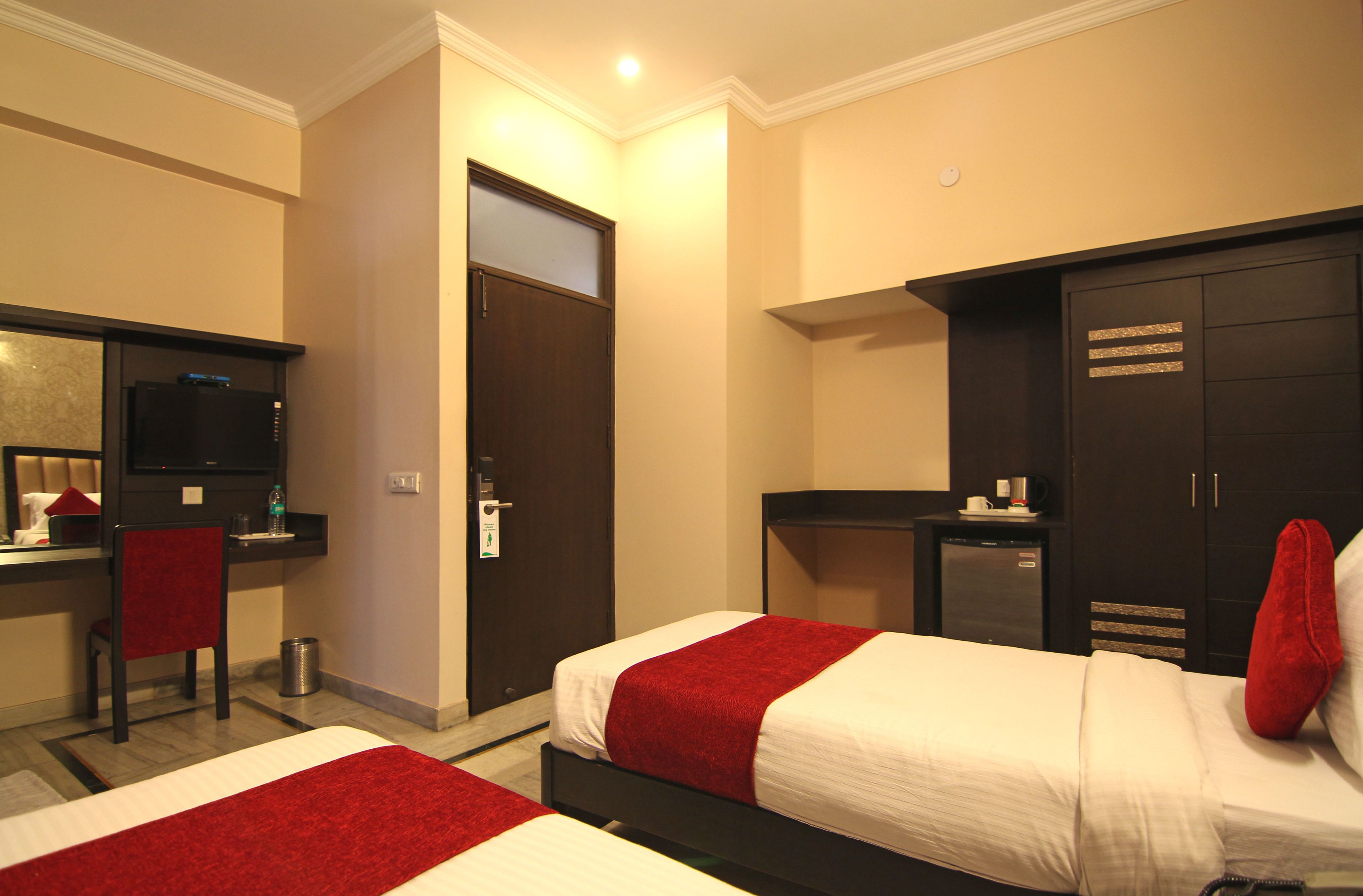 Een hotelkamer met twee bedden, een bureau, een stoel, een televisie en een kledingkast.