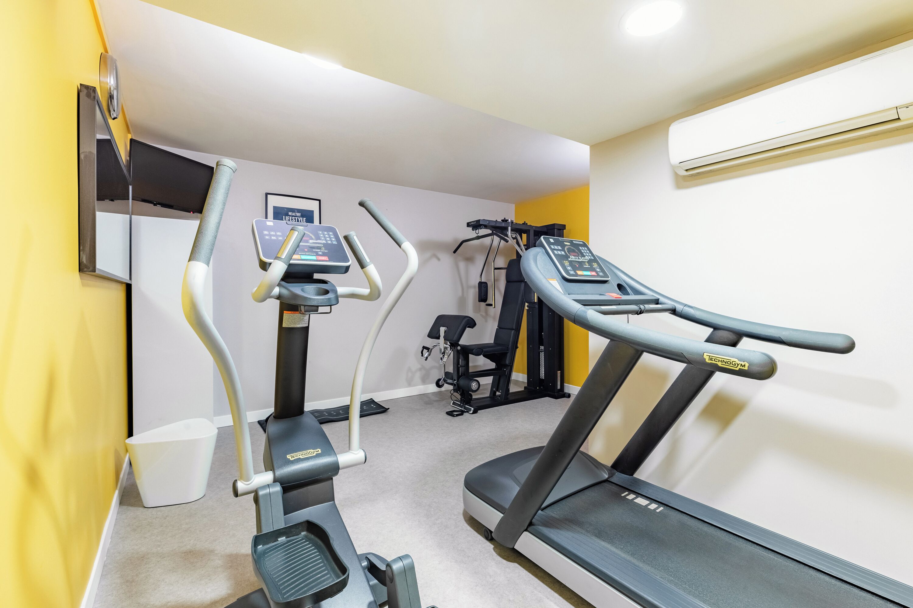 A gym with treadmills, elliptical machines, and a weight bench.