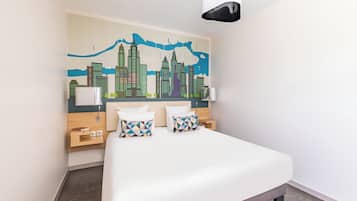 Habitación de hotel con una cama grande, dos mesitas de noche, un cabecero con un mural de la ciudad y una lámpara moderna.