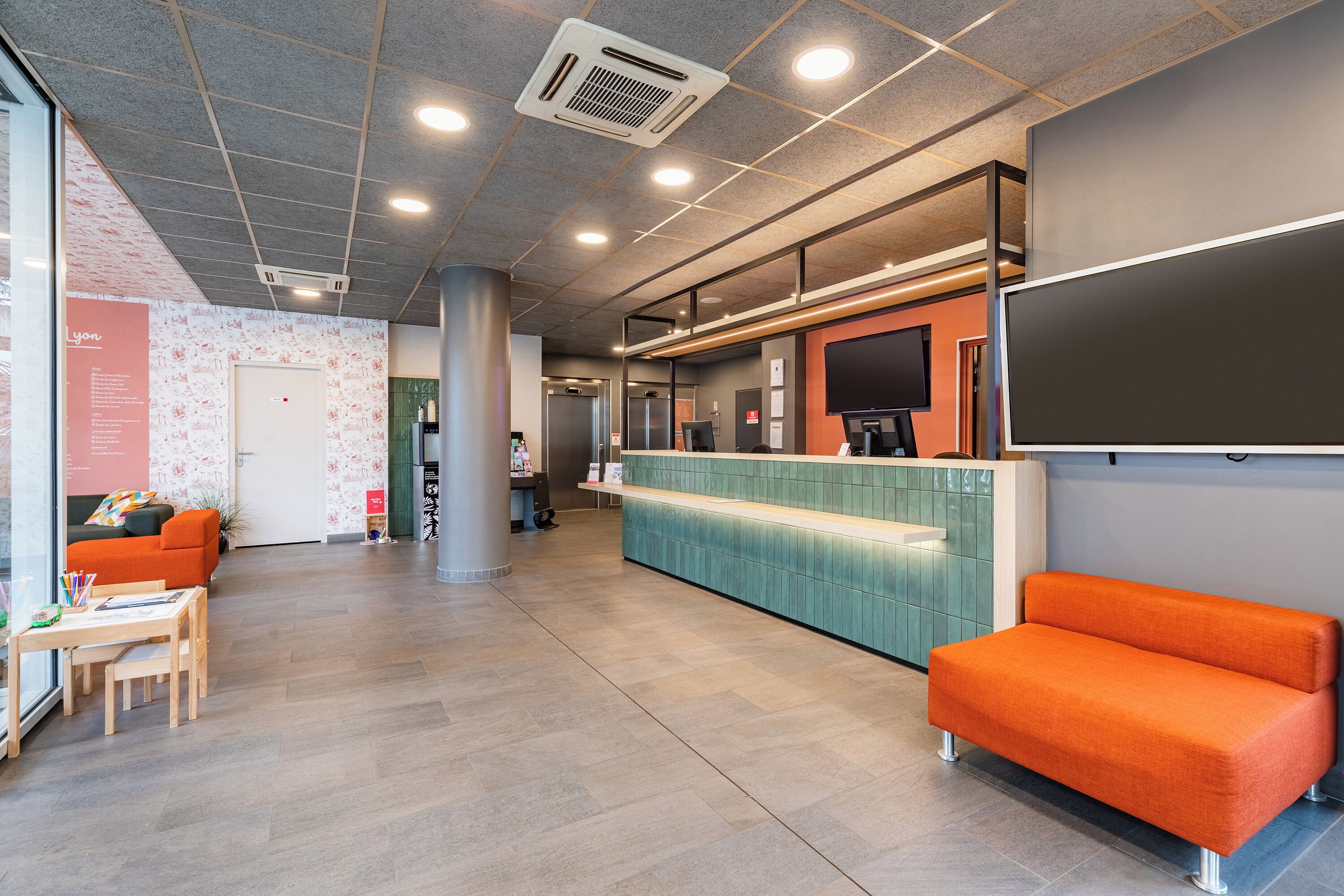A reception area with a counter, seating, and a large screen.